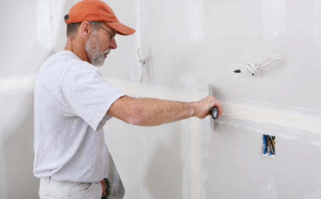 Applying drywall joint compound with a trowel on the sheetrock wall surface