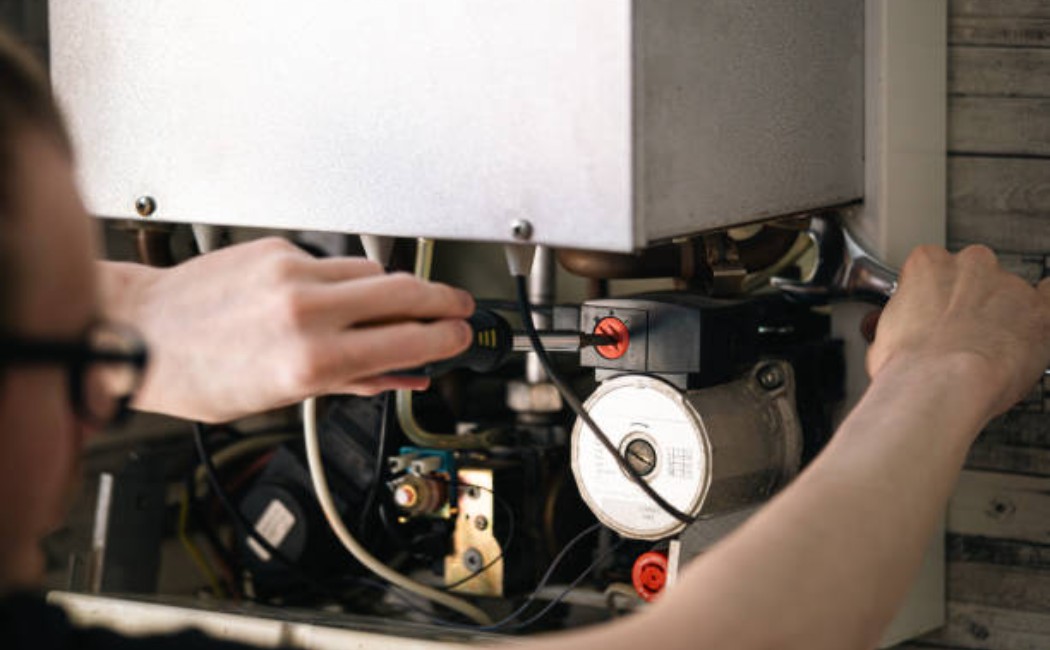 Man repairing a heating boiler with a screwdriver and wrench.