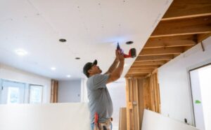 Two craftsmen at work fitting kitchen drywall on a renovation site