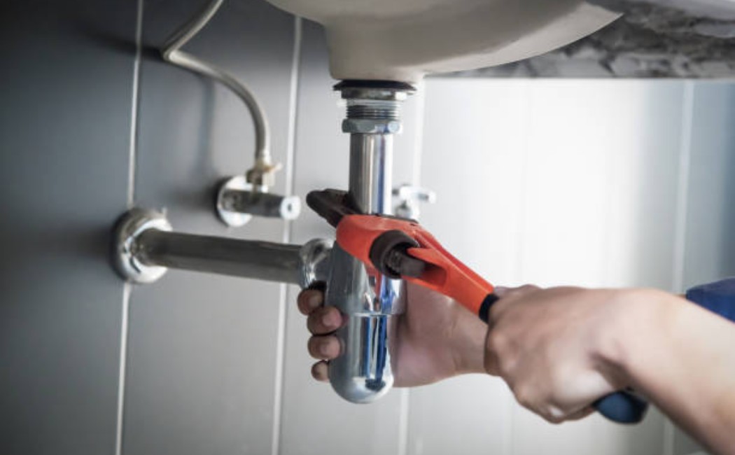 Plumber repairing water pipe under kitchen sink