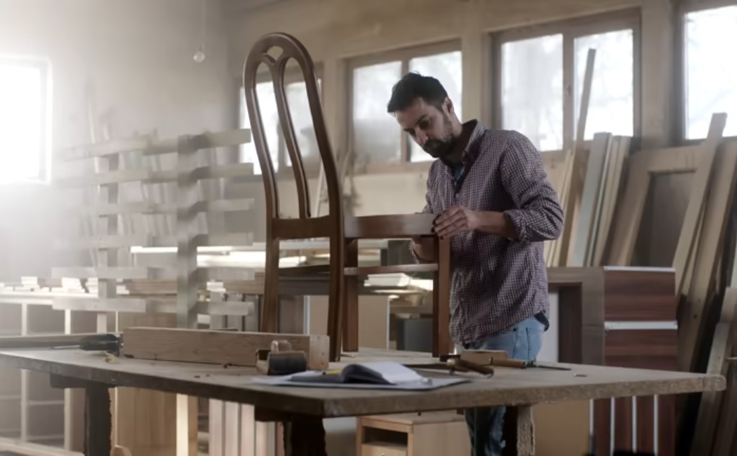 Furniture craftsman assembling a chair with tools.