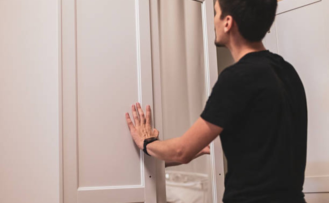 istockphoto-2228964290-612x612_1050x650_q90 Male closing closet doors in a clean bedroom setting.