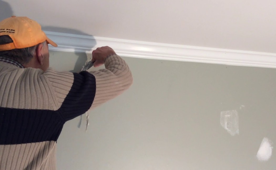 Worker applying joint compound along wall trim during Drywall Repair Services in a residential interior.