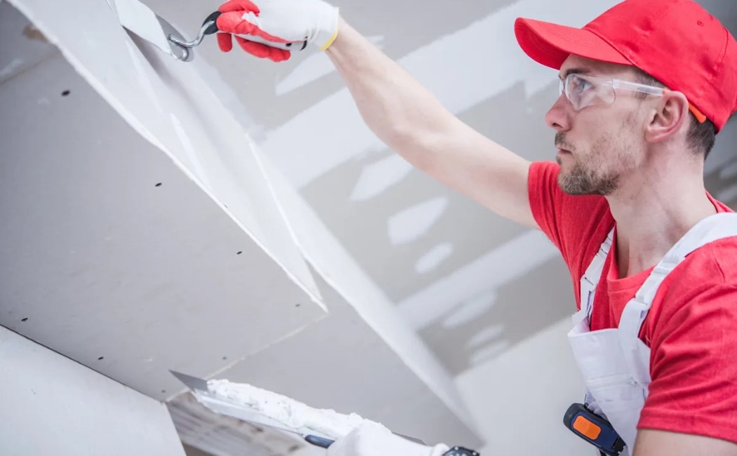 Worker applying compound for drywall repairs works How Much Does Drywall Repair Cost?