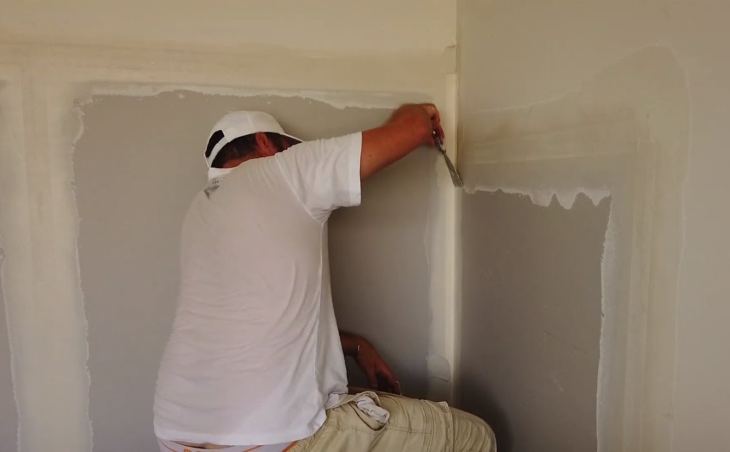 A professional applying joint compound to a wall corner for seamless finishing during Drywall Repair Services.