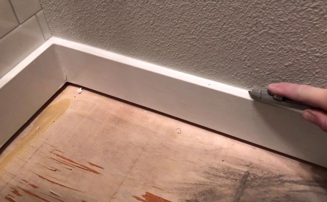 A molding repair professional trimming and fitting a baseboard molding for a precise repair and seamless wall finish.