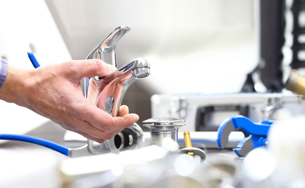 Expert Plumbing Company Faucet Installation. A professional from a plumbing company installing a modern bathroom faucet with plumbing tools during a sink fixture replacement.